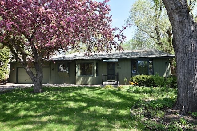 single story home with a garage, a front yard, and concrete driveway