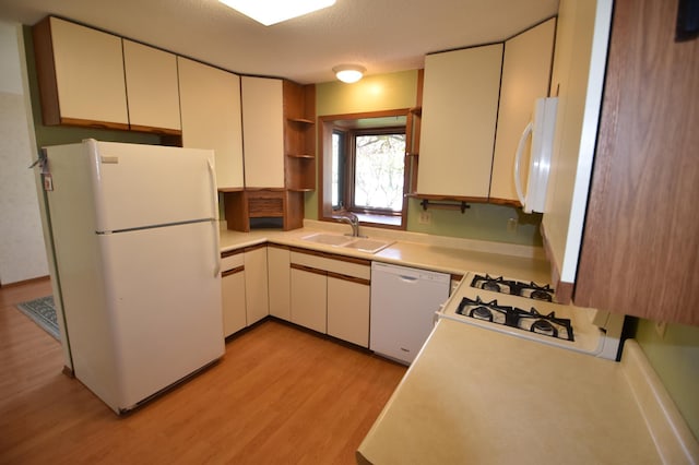 kitchen with white appliances, a sink, light wood-type flooring, and light countertops