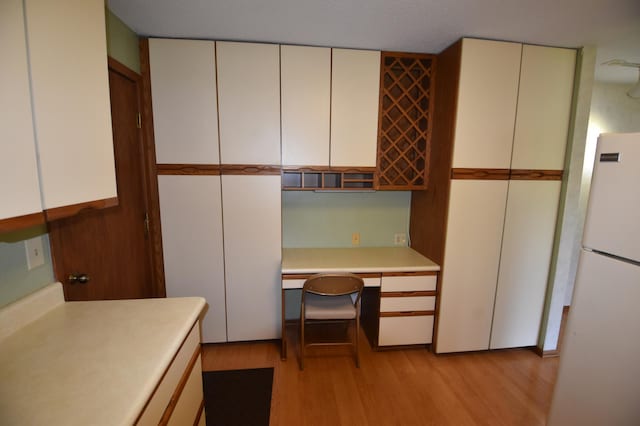 kitchen with freestanding refrigerator, light countertops, and light wood finished floors