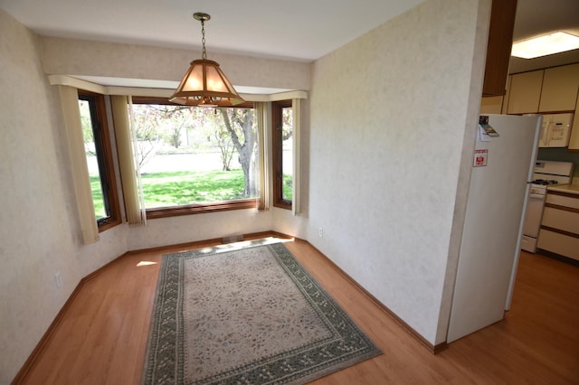 unfurnished dining area featuring wood finished floors and baseboards