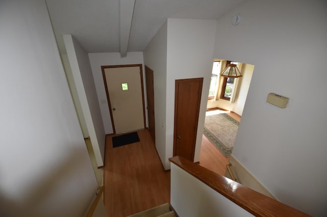 hall featuring wood finished floors, an upstairs landing, and baseboards