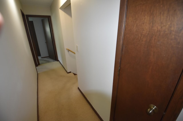 hallway with light carpet and an upstairs landing