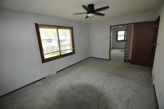 carpeted empty room featuring a ceiling fan and baseboards