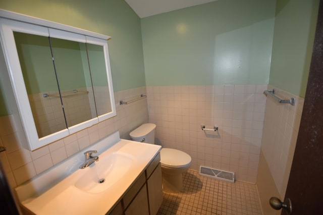 bathroom featuring tile walls, toilet, a wainscoted wall, vanity, and tile patterned floors