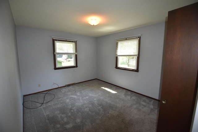 spare room featuring healthy amount of natural light, carpet floors, and baseboards