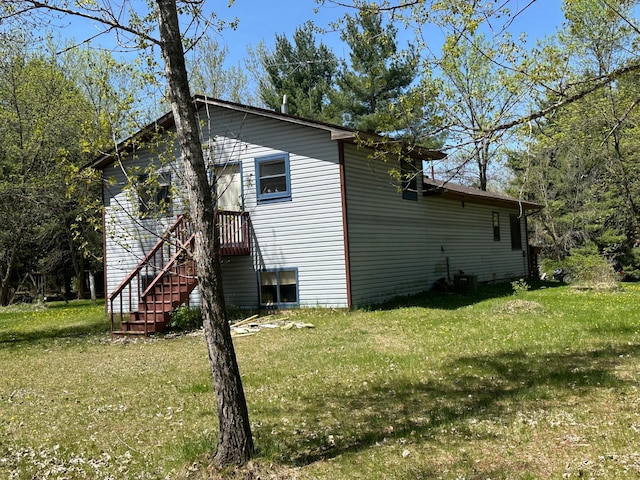 view of property exterior with a lawn and stairs