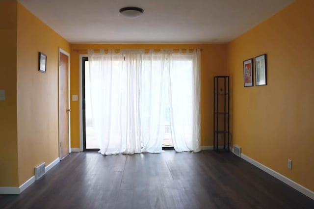 unfurnished room featuring plenty of natural light, dark wood finished floors, and baseboards