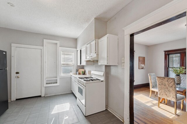 3413 Columbus Ave, Minneapolis, MN 55407 - kitchen featuring gas range gas stove, under cabinet range hood, white cabinets, a textured ceiling, and baseboards