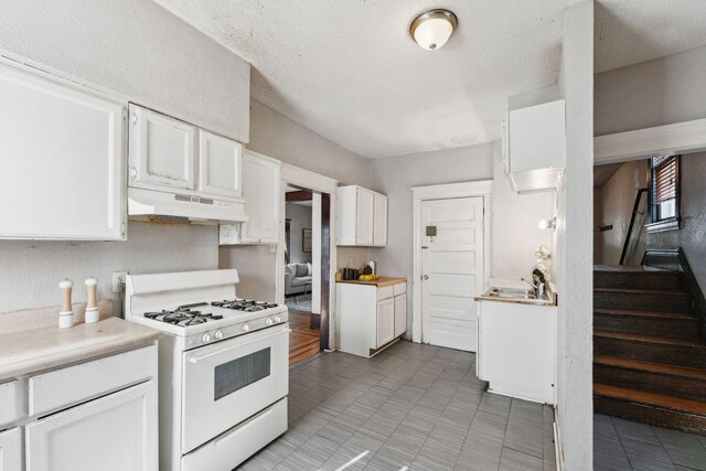 3413 Columbus Ave, Minneapolis, MN 55407 - kitchen featuring white gas range, under cabinet range hood, white cabinetry, light countertops, and a sink
