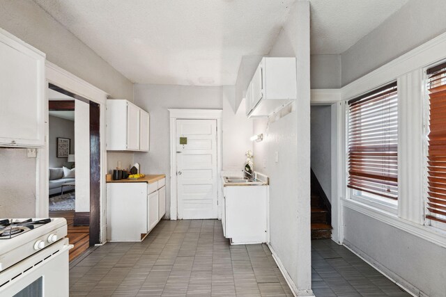 3413 Columbus Ave, Minneapolis, MN 55407 - kitchen featuring white cabinets, white gas range, light countertops, and baseboards
