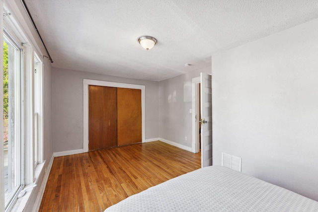3413 Columbus Ave, Minneapolis, MN 55407 - unfurnished bedroom with wood finished floors, a closet, baseboards, and a textured ceiling