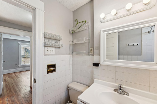 3413 Columbus Ave, Minneapolis, MN 55407 - bathroom with toilet, wood-type flooring, tile walls, vanity, and a textured ceiling