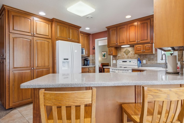 27180 Lakewood Dr NW, Stanford Twp, MN 55040 - kitchen featuring white appliances, a peninsula, light stone countertops, a kitchen bar, and decorative backsplash