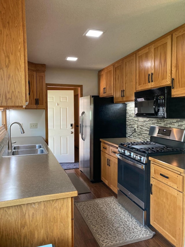 875 20th St, Windom, MN 56101 - kitchen featuring appliances with stainless steel finishes, a sink, dark wood-type flooring, decorative backsplash, and a textured ceiling