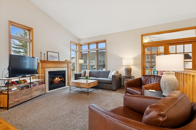 living room featuring healthy amount of natural light, a fireplace with flush hearth, and high vaulted ceiling