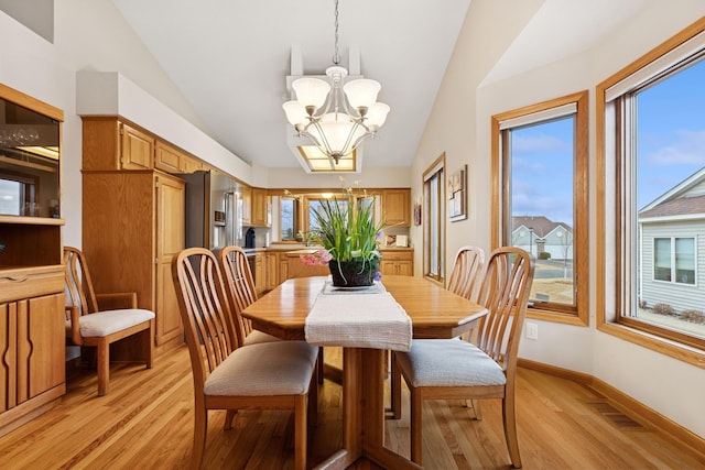 dining space with lofted ceiling, a chandelier, light wood-style flooring, healthy amount of natural light, and baseboards