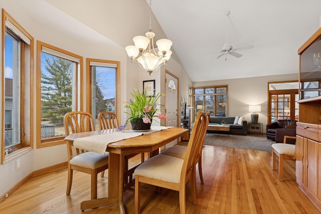 dining room featuring lofted ceiling, healthy amount of natural light, a ceiling fan, light wood-style floors, and a chandelier