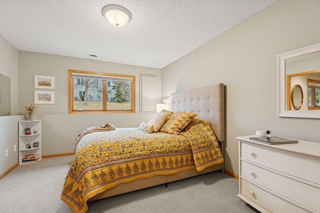 bedroom with light colored carpet, baseboards, and a textured ceiling