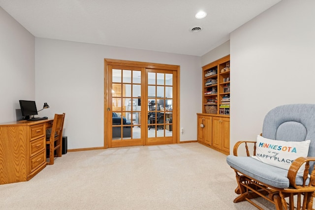 sitting room with light colored carpet, a desk, and baseboards