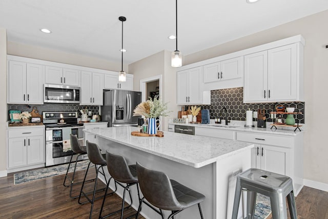968 150th Ave, New Richmond, WI 54017 - kitchen featuring stainless steel appliances, a sink, a kitchen island, decorative backsplash, and a kitchen bar