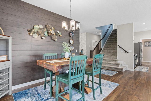 968 150th Ave, New Richmond, WI 54017 - dining area featuring stairway, wooden walls, a chandelier, wood finished floors, and baseboards