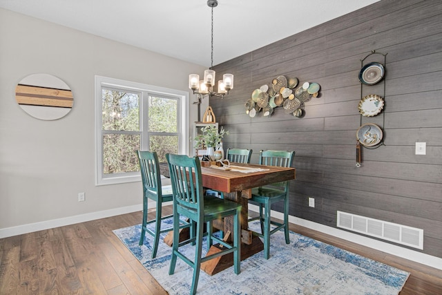 968 150th Ave, New Richmond, WI 54017 - dining area with baseboards, wood walls, a chandelier, and wood finished floors