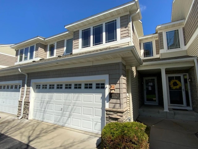 view of side of property with an attached garage, stone siding, and driveway