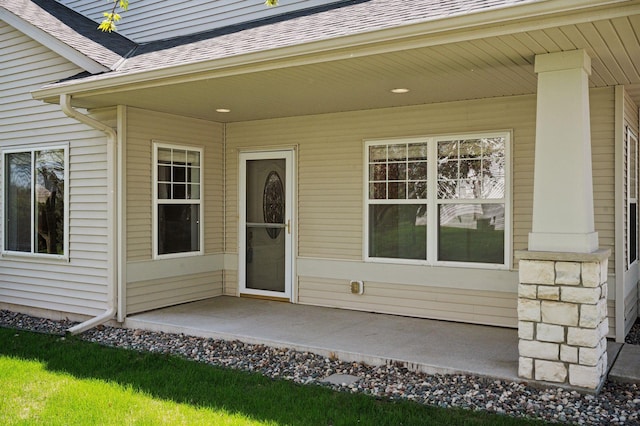 view of exterior entry featuring roof with shingles