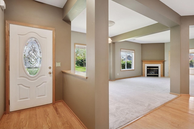 entrance foyer with wood finished floors, baseboards, and a glass covered fireplace