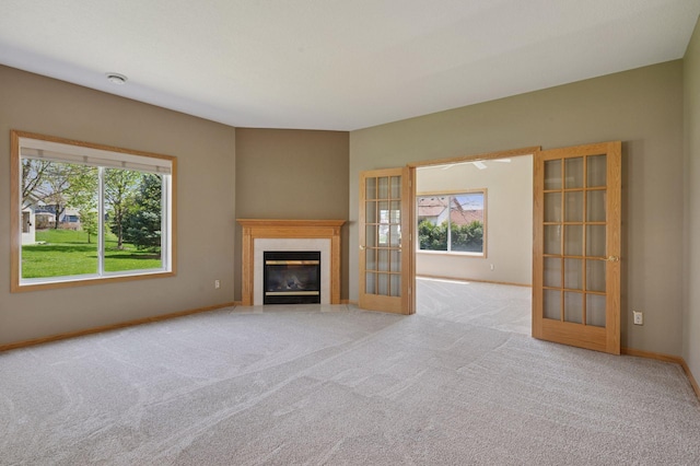 unfurnished living room with a tile fireplace, plenty of natural light, carpet flooring, and french doors