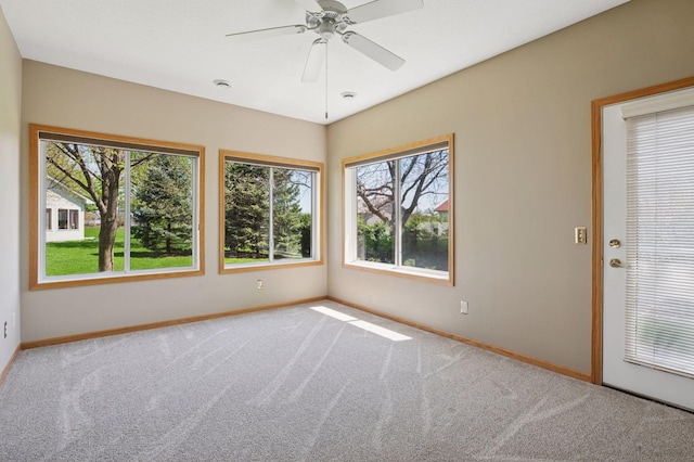 carpeted empty room featuring baseboards and a ceiling fan