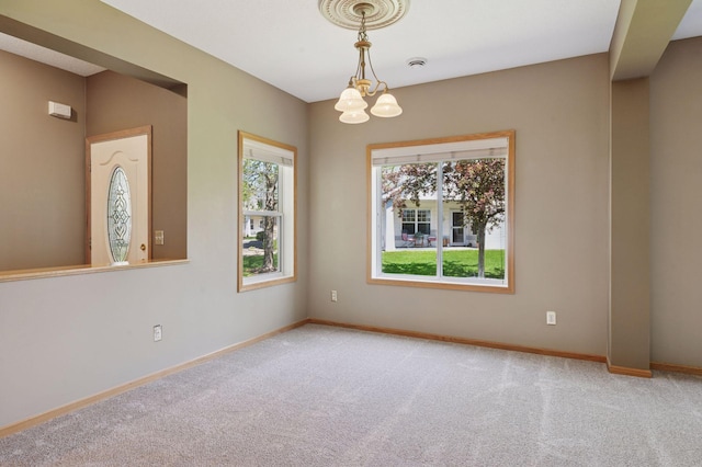 spare room featuring light carpet, baseboards, and a chandelier