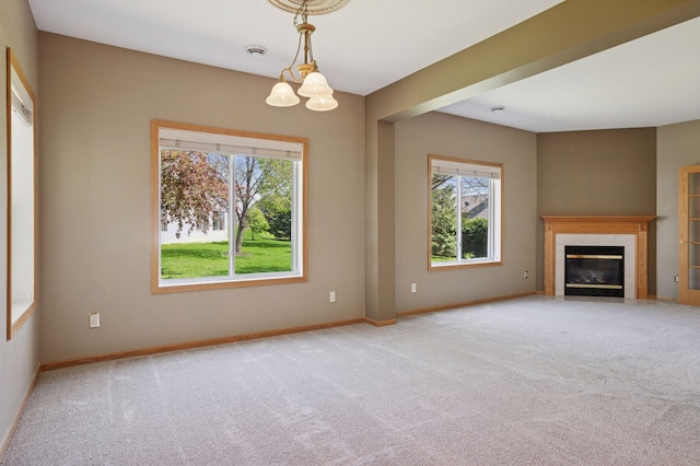 unfurnished living room featuring carpet, a fireplace, baseboards, and a chandelier