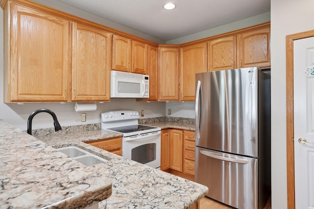 kitchen featuring white appliances, a sink, light stone counters, and recessed lighting