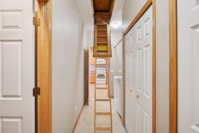 hallway featuring washer and clothes dryer and baseboards