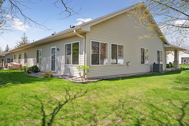 rear view of property featuring central AC unit and a lawn