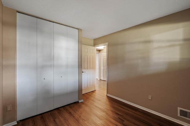 10276 Hanson Blvd NW, Coon Rapids, MN 55433 - unfurnished bedroom with dark wood-style flooring, baseboards, and a closet