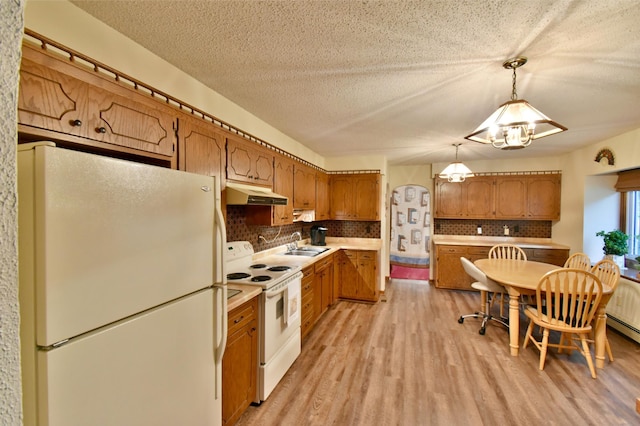 1300 10th St NE, Sauk Rapids Twp, MN 56379 - kitchen with white appliances, under cabinet range hood, light wood-style floors, tasteful backsplash, and brown cabinets