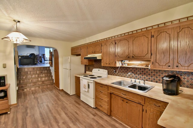 1300 10th St NE, Sauk Rapids Twp, MN 56379 - kitchen with white appliances, under cabinet range hood, light wood-style floors, decorative backsplash, and a textured ceiling