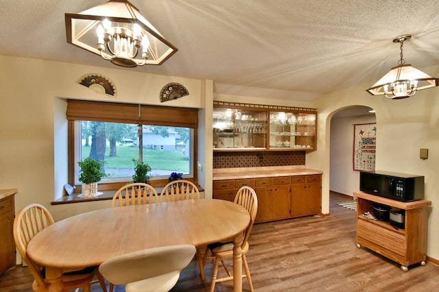 1300 10th St NE, Sauk Rapids Twp, MN 56379 - dining area with a chandelier, arched walkways, light wood-style floors, and a textured ceiling