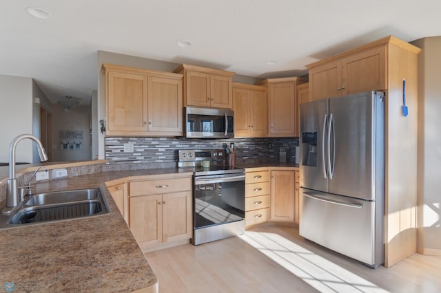 kitchen with appliances with stainless steel finishes, a sink, light brown cabinetry, light wood-style floors, and recessed lighting