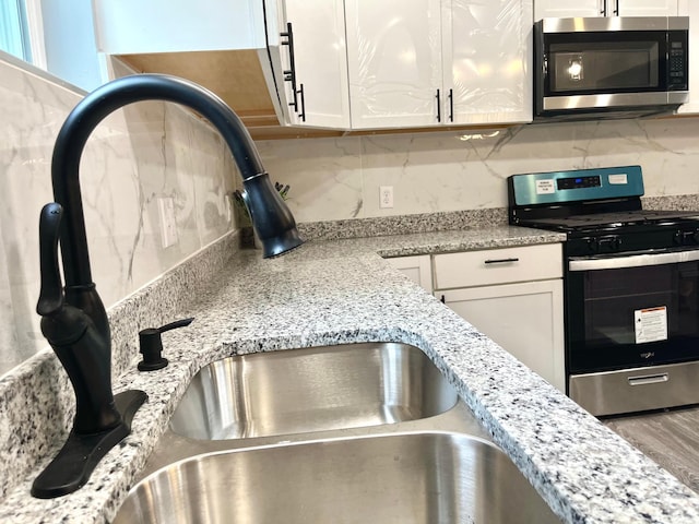 2616 30th Ave S, Minneapolis, MN 55406 - kitchen view of stainless steel appliances, a sink, decorative backsplash, and white cabinetry