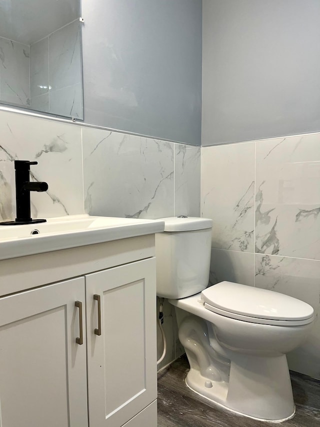 2616 30th Ave S, Minneapolis, MN 55406 - half bathroom featuring tile walls, toilet, vanity, and wood finished floors