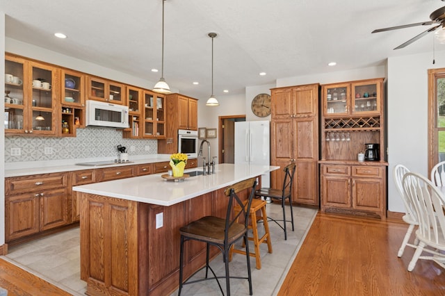 6715 Eldorado Way, Leon Twp, MN 55009 - kitchen with white appliances, brown cabinets, a sink, light wood-type flooring, and a kitchen island with sink