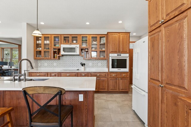 6715 Eldorado Way, Leon Twp, MN 55009 - kitchen featuring white appliances, a sink, brown cabinets, a kitchen bar, and decorative backsplash