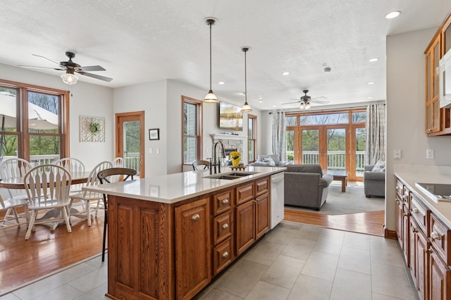 6715 Eldorado Way, Leon Twp, MN 55009 - kitchen featuring a sink, a ceiling fan, brown cabinets, white dishwasher, and a fireplace