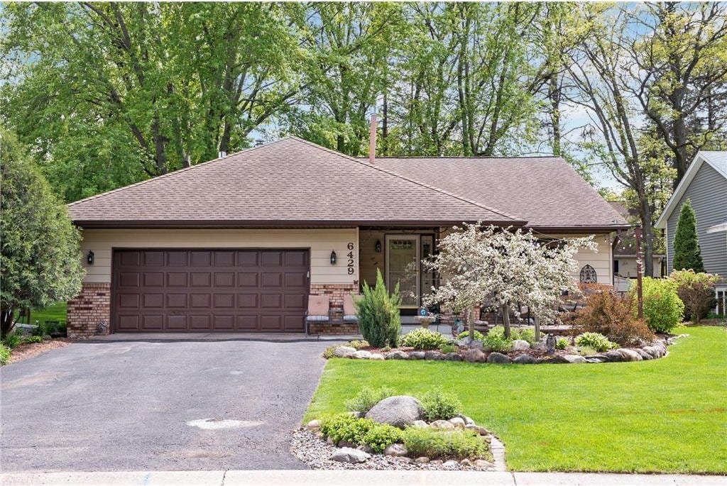 view of front of home featuring driveway, an attached garage, brick siding, and a front yard