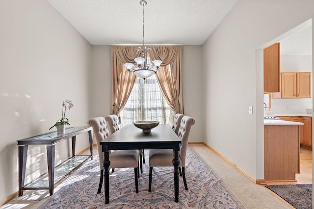 dining area with a chandelier, light colored carpet, a textured ceiling, and baseboards