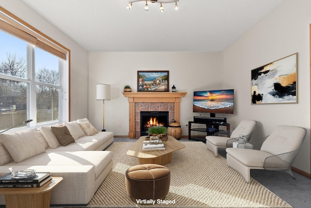 living area with a tiled fireplace, carpet flooring, and baseboards