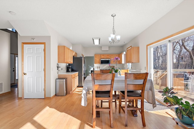 dining space with light wood-style flooring, a chandelier, and baseboards